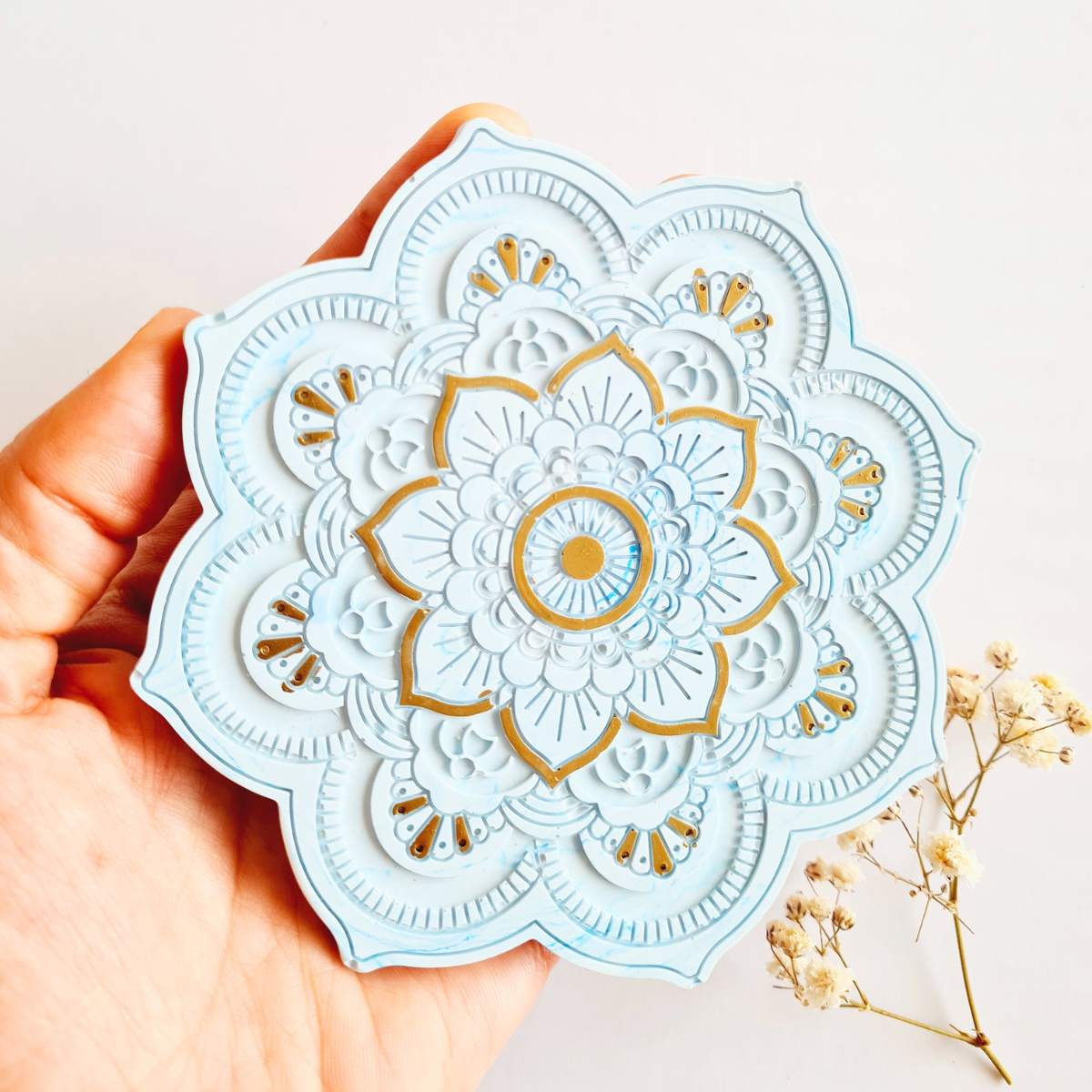 Hand holding a Flower shape blue and gold mandala ring dish/ coaster on white background