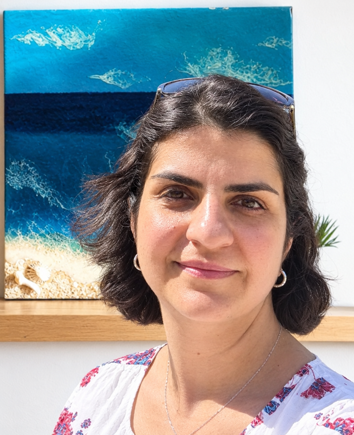 Mitra the founder  standing in front of a framed beach-themed painting.