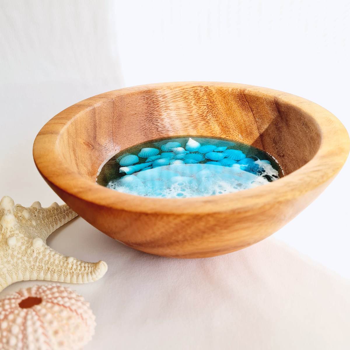 wooden bowl with resin ocean art and shells inside on a white background