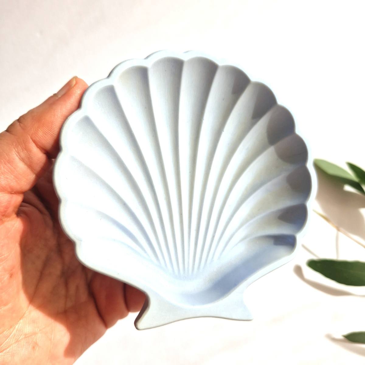 A blue handrafted shell trinket dish on a white background