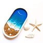 a handcrafted ocean themed tray on a white surface with a few shells