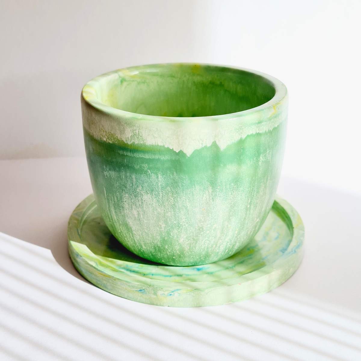 a green plant pot with saucer on a white background 