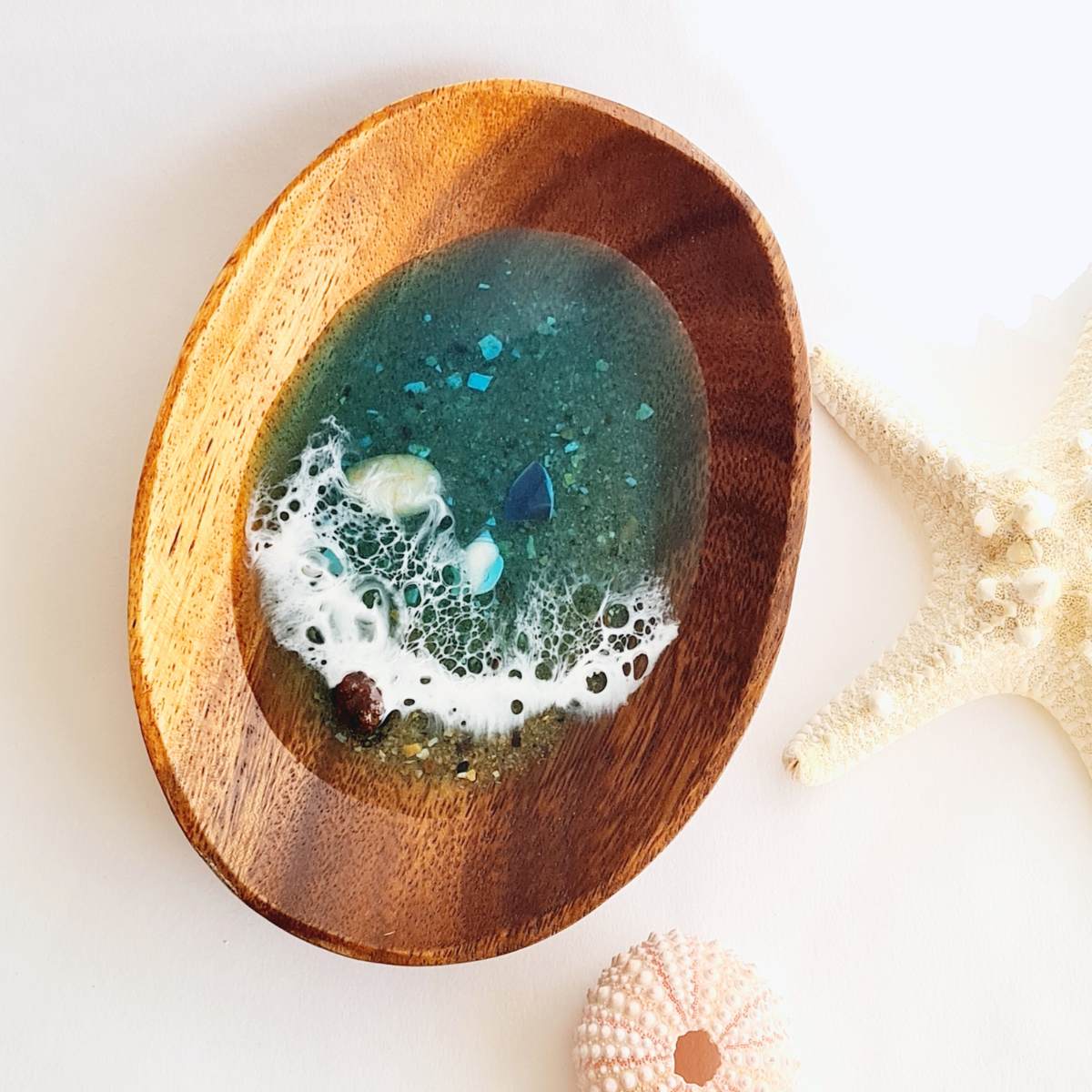 a wooden jewellery dish with resin ocean art on a white background