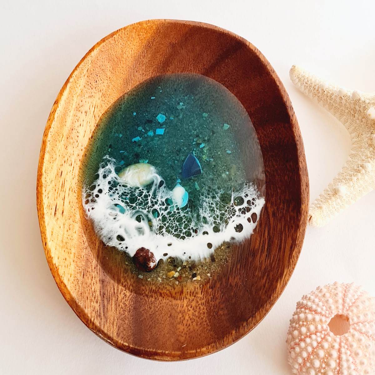 a wooden jewellery dish with resin ocean art on a white background