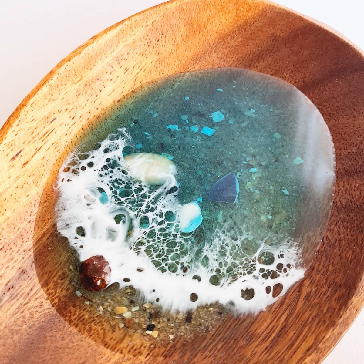 close up of a wooden jewellery dish with resin ocean art on a white background