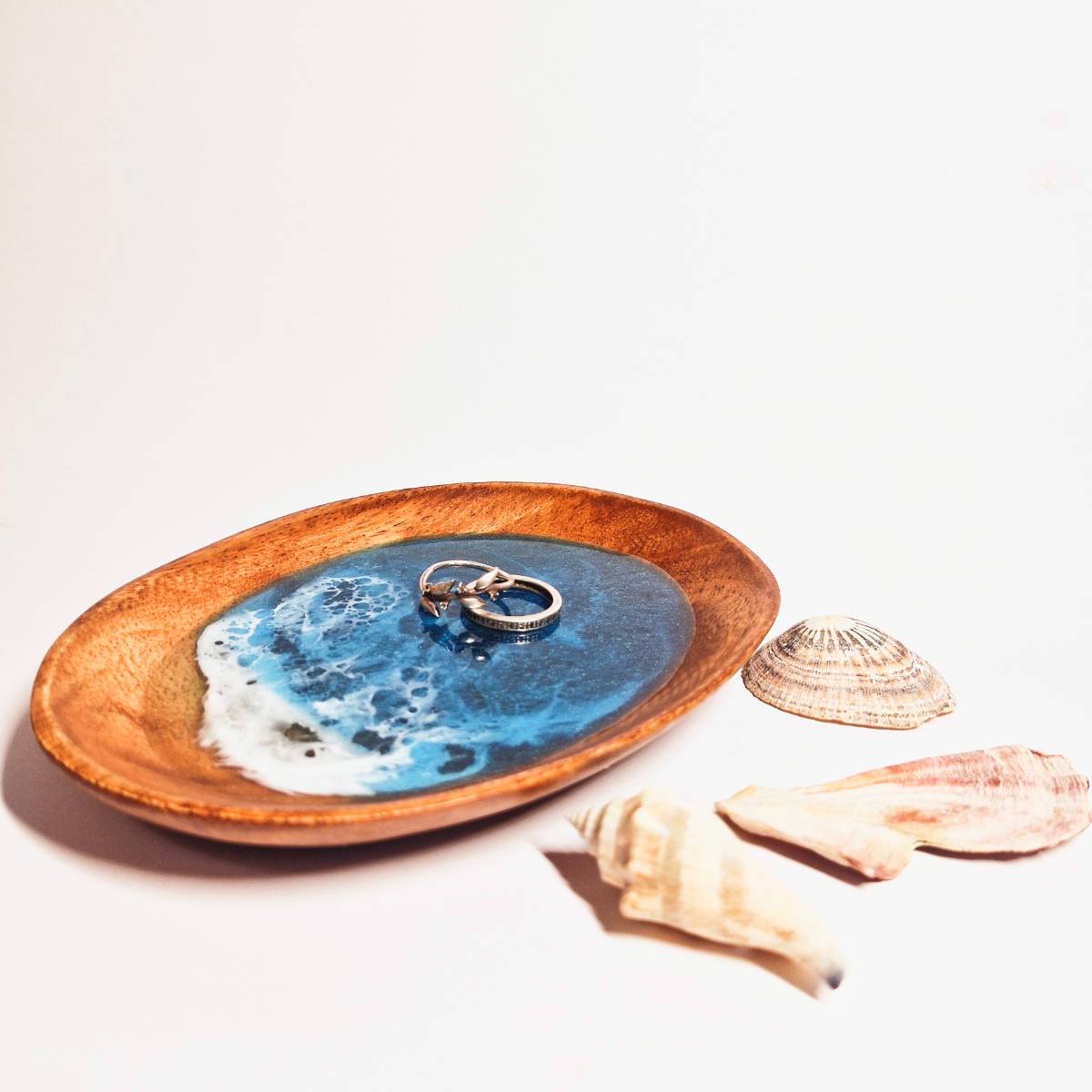 wooden oval dish with ocean resin art - with two rings on top - on a white background