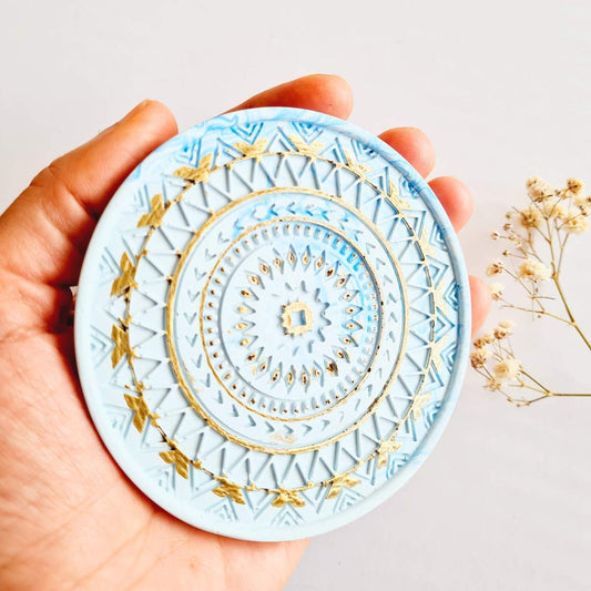 Hand holding a blue and gold mandala ring dish